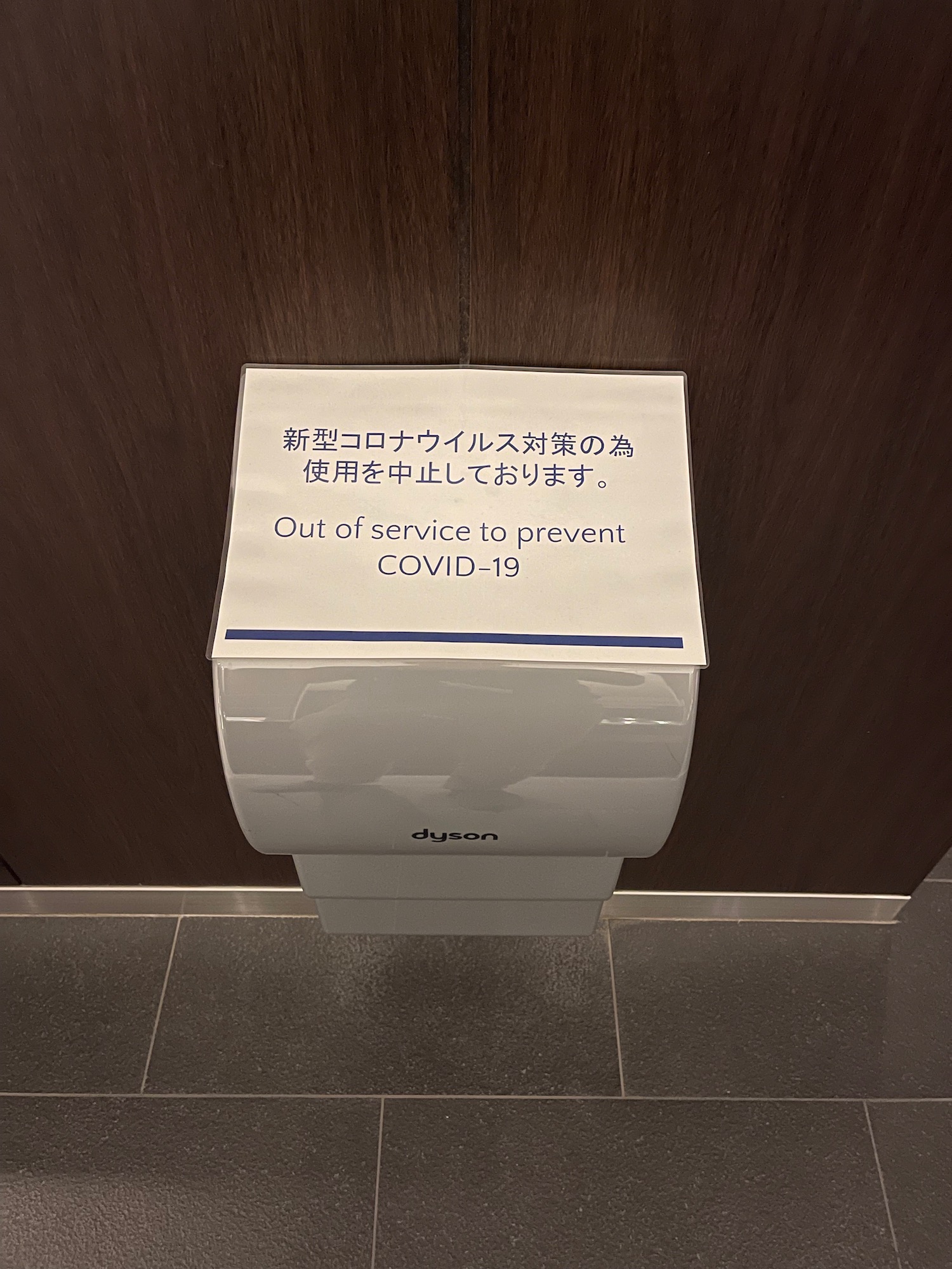 a white paper towel dispenser with a sign on the wall