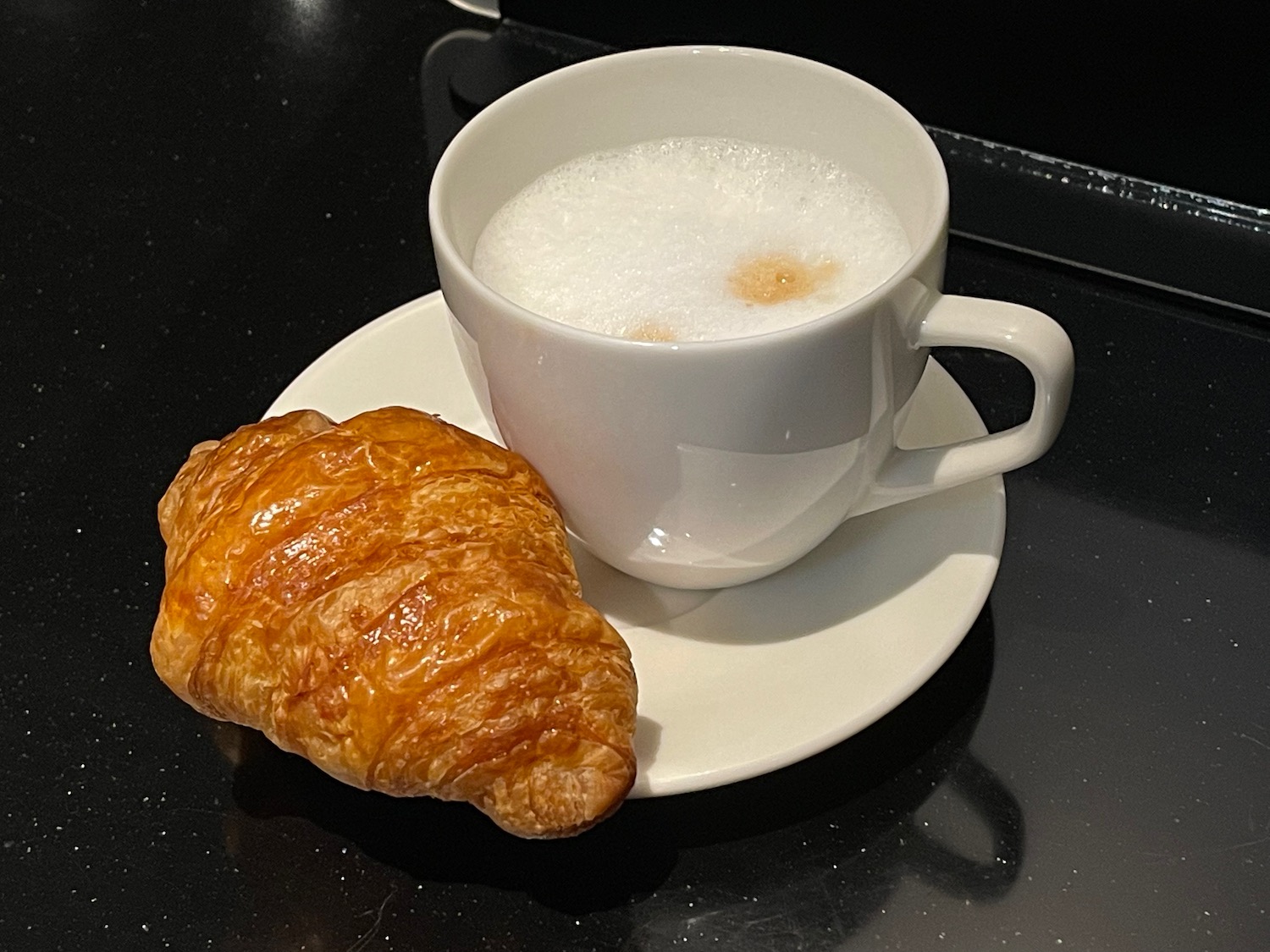 a croissant and a cup of coffee on a saucer