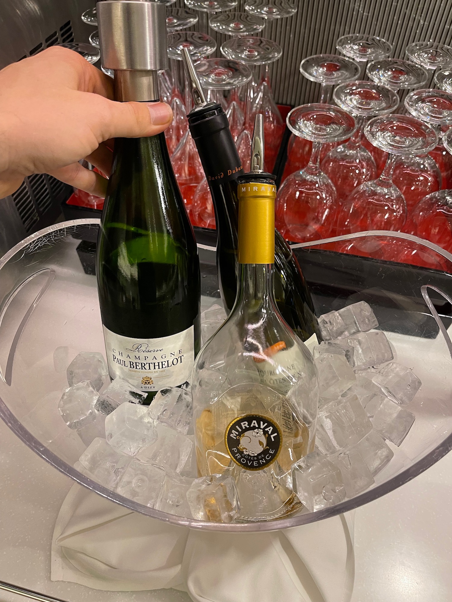 a hand holding a bottle of wine in a bowl of ice