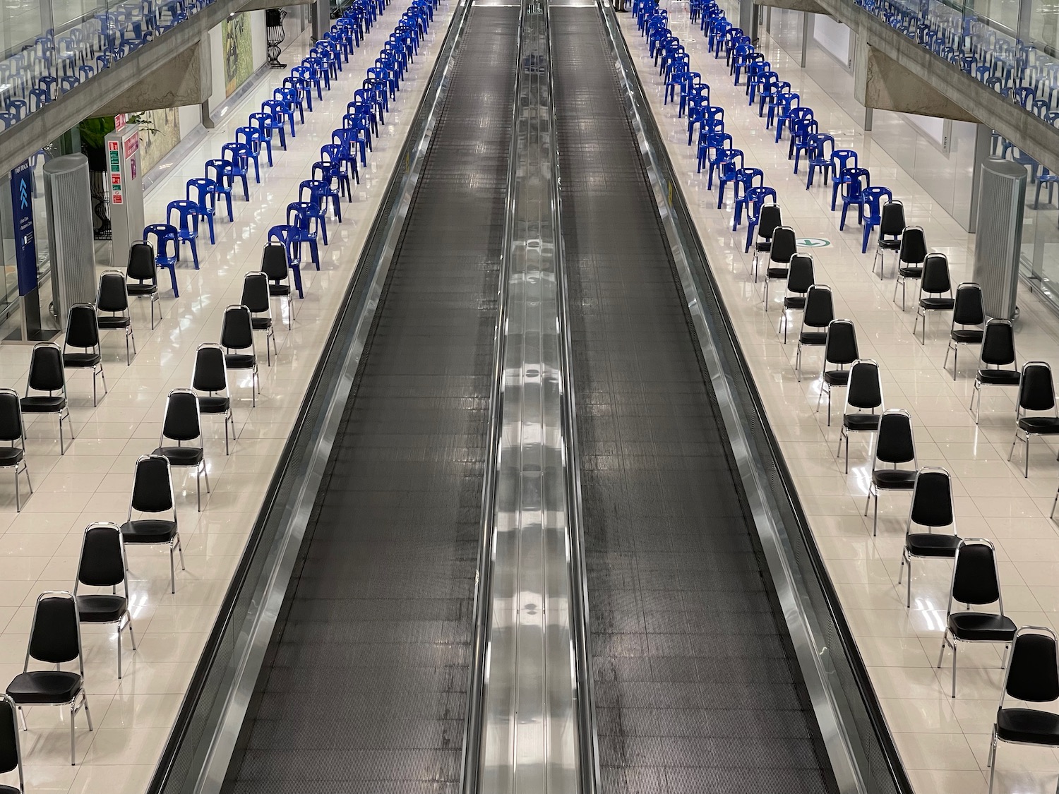 a large airport terminal with blue chairs and a walkway