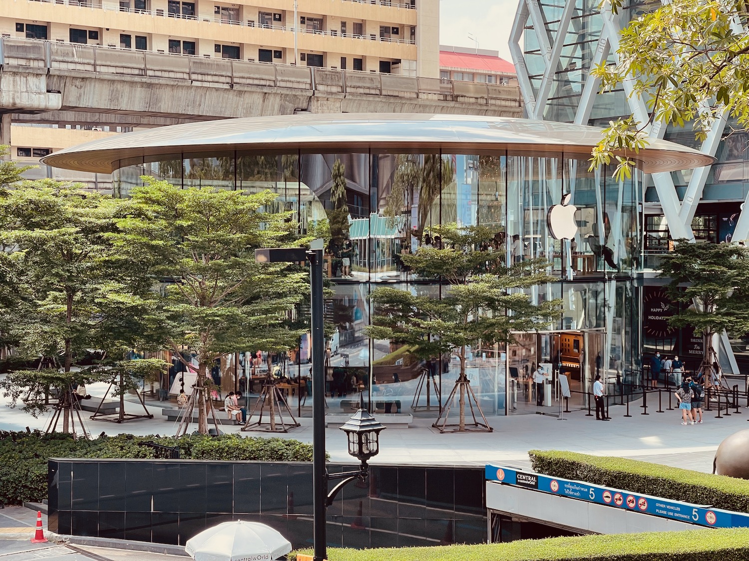 a glass building with trees and a group of people