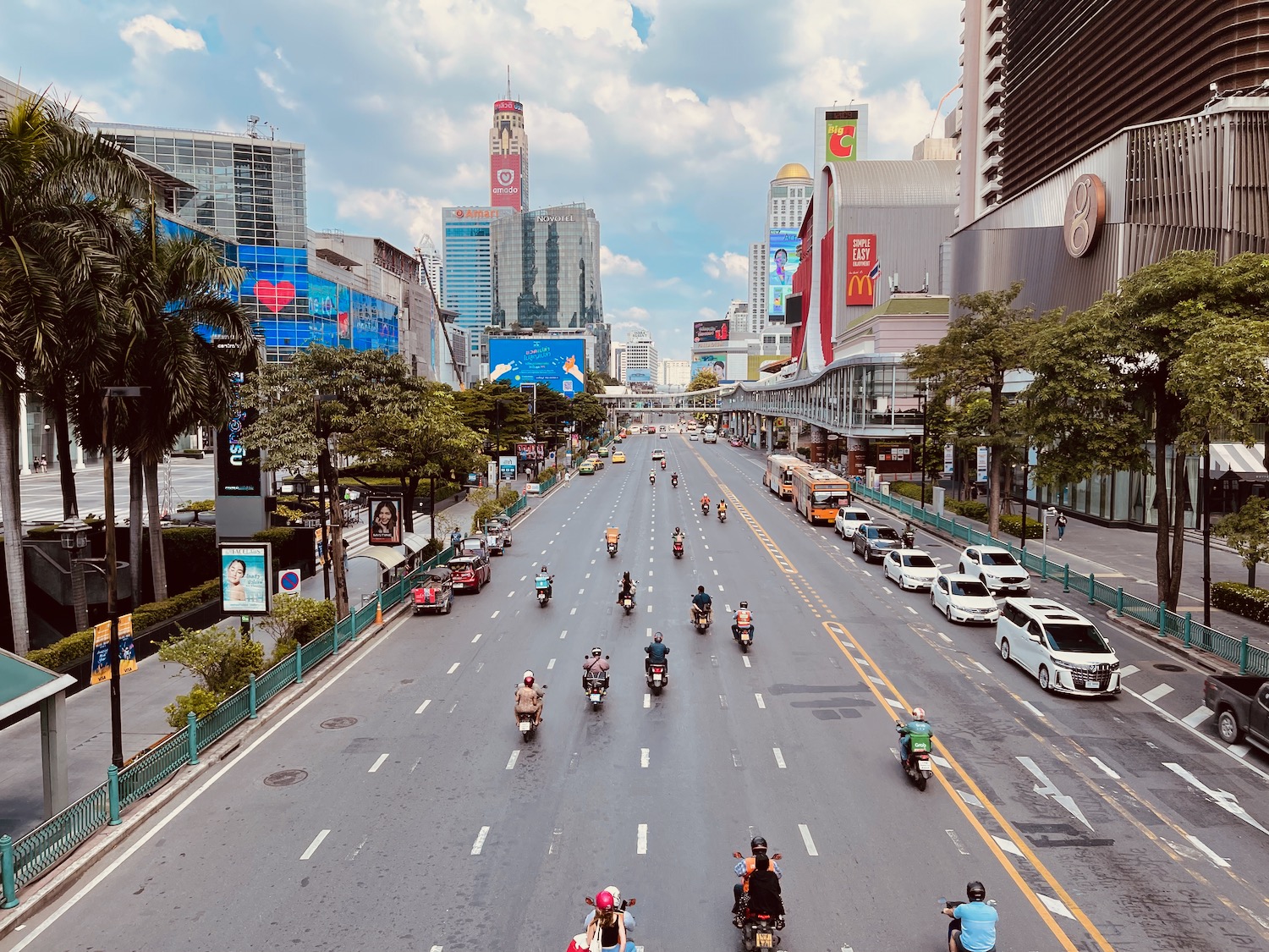 a group of people on motorcycles on a street with buildings and trees