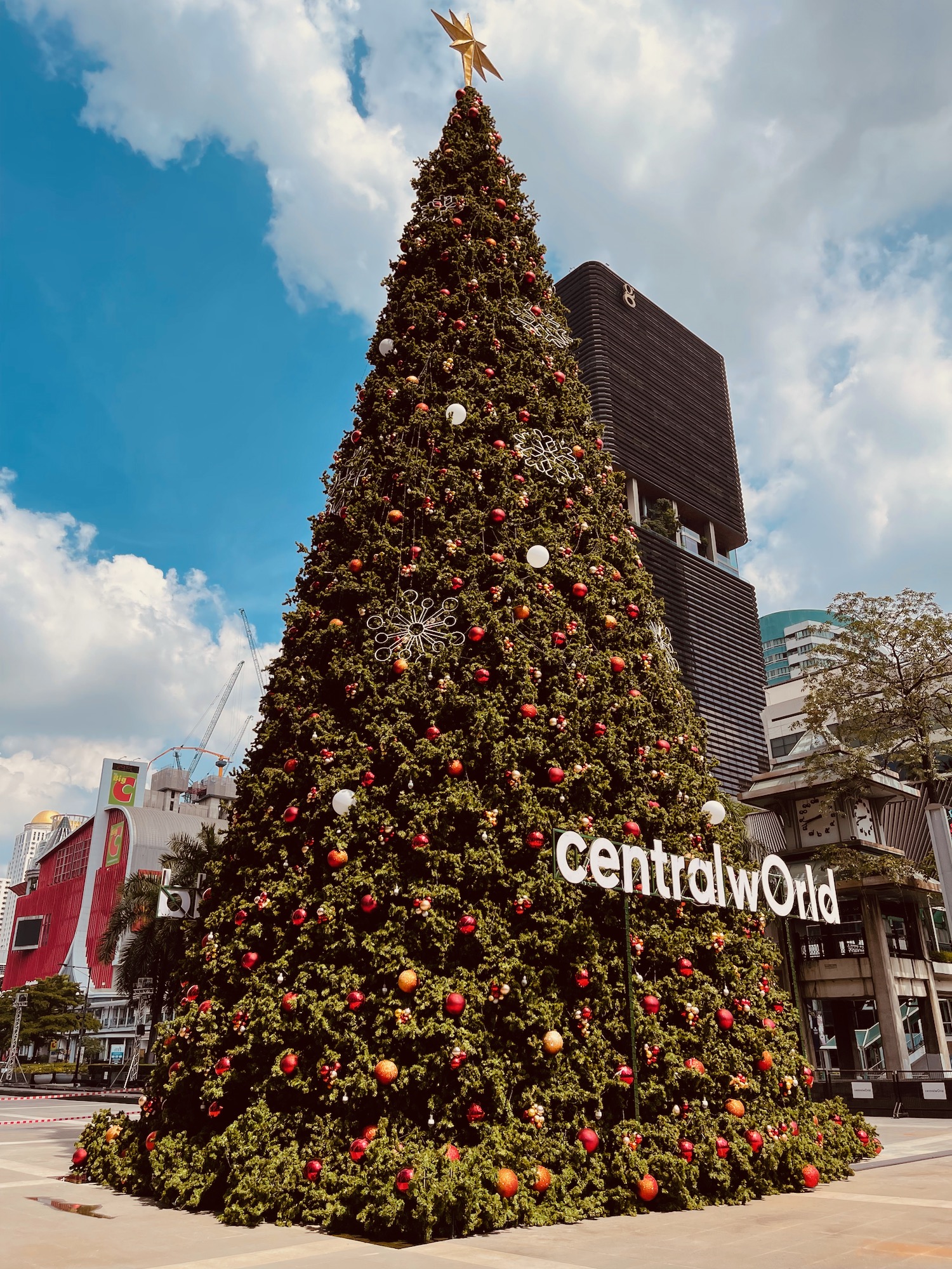 a large tree with ornaments and a sign in the background