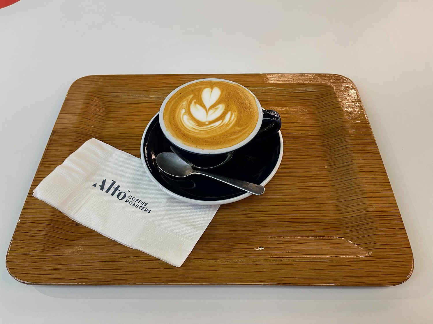 a cup of coffee with a spoon and a napkin on a tray