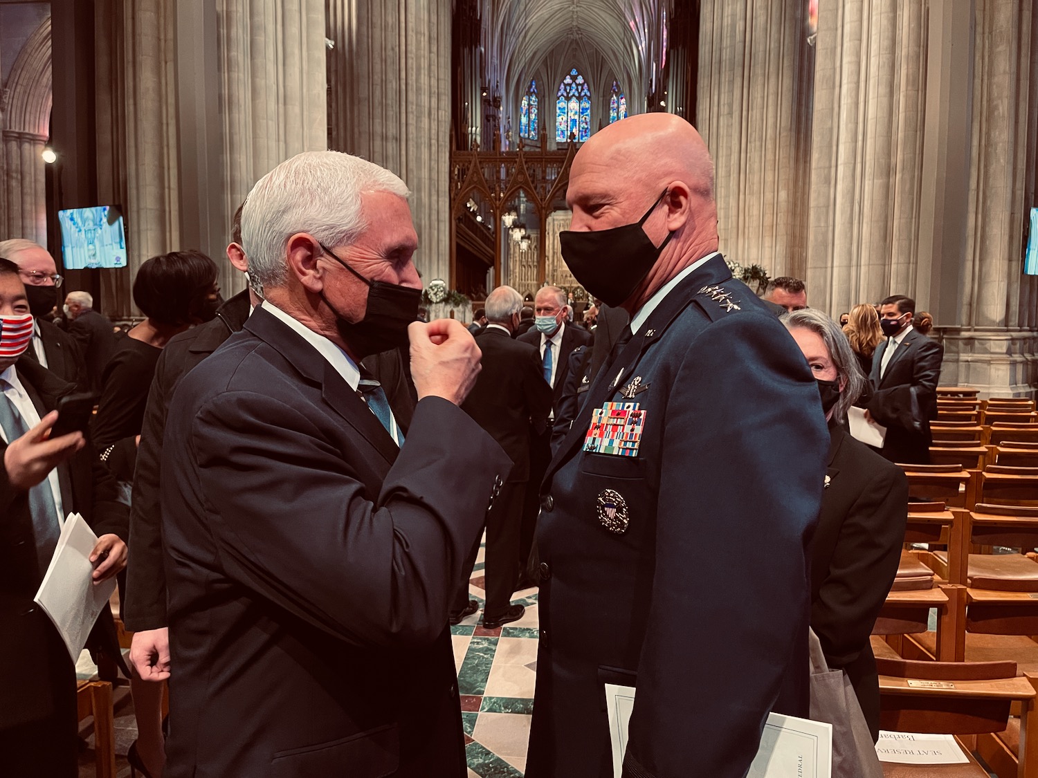 a man wearing a face mask to another man in a church