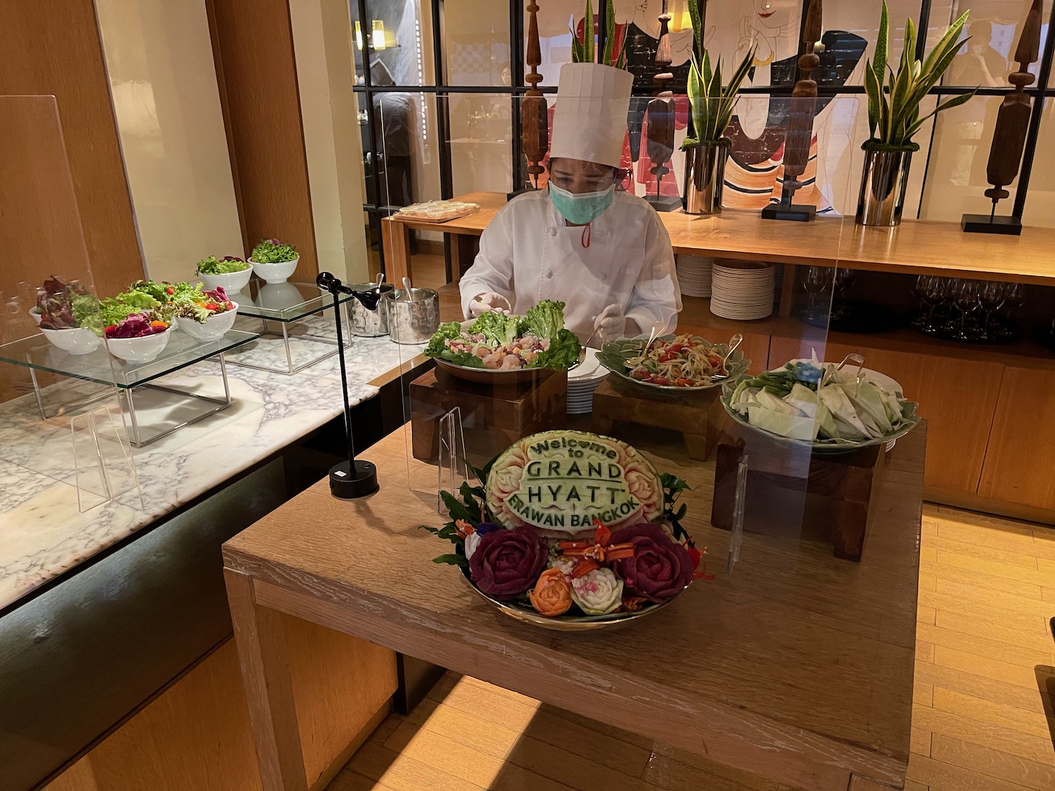 a person in a white uniform and mask standing behind a table with food