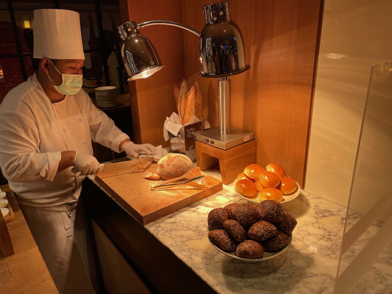 a person in a chef's uniform cutting bread