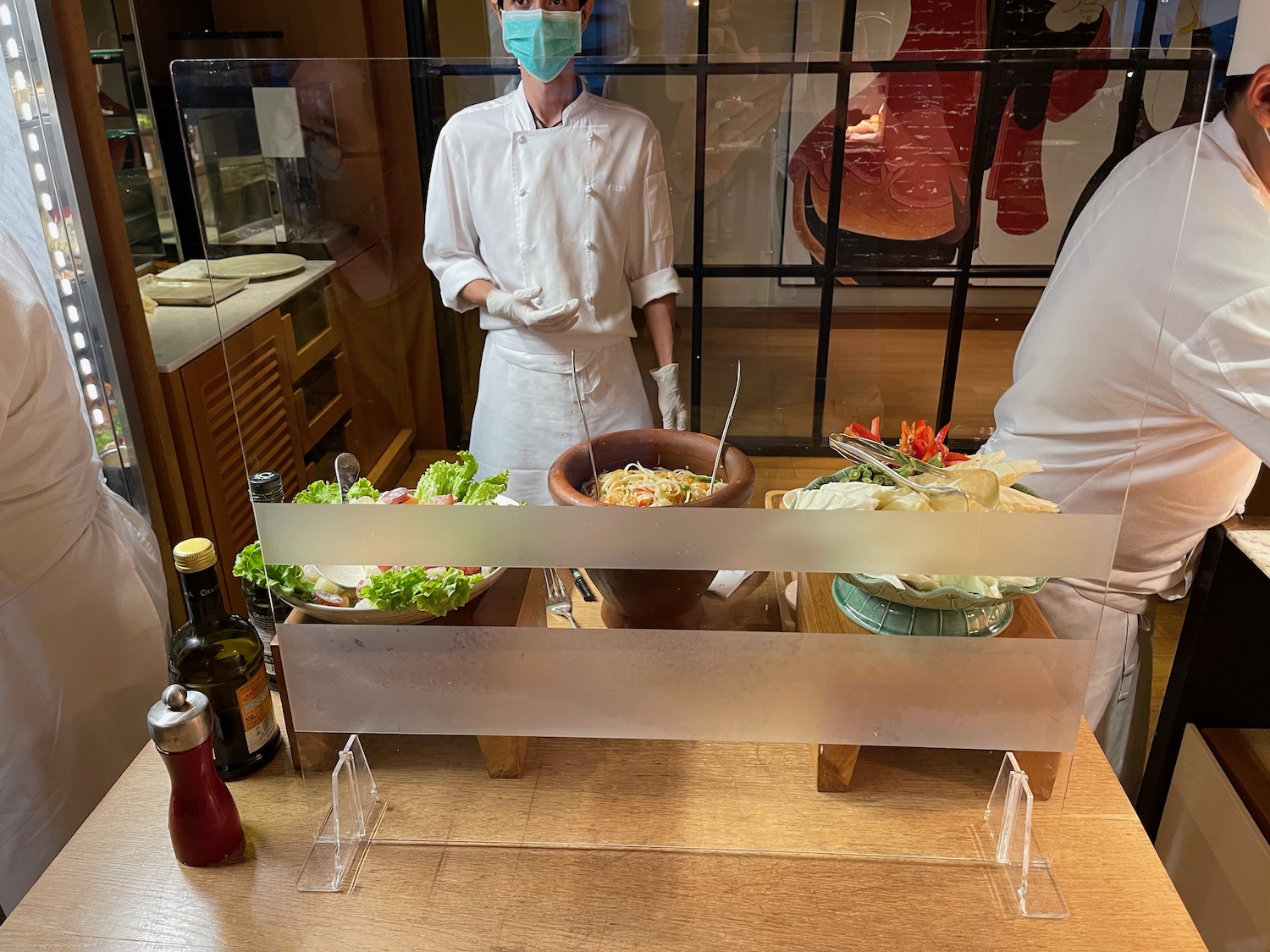 a chef wearing a face mask standing in front of a table with food