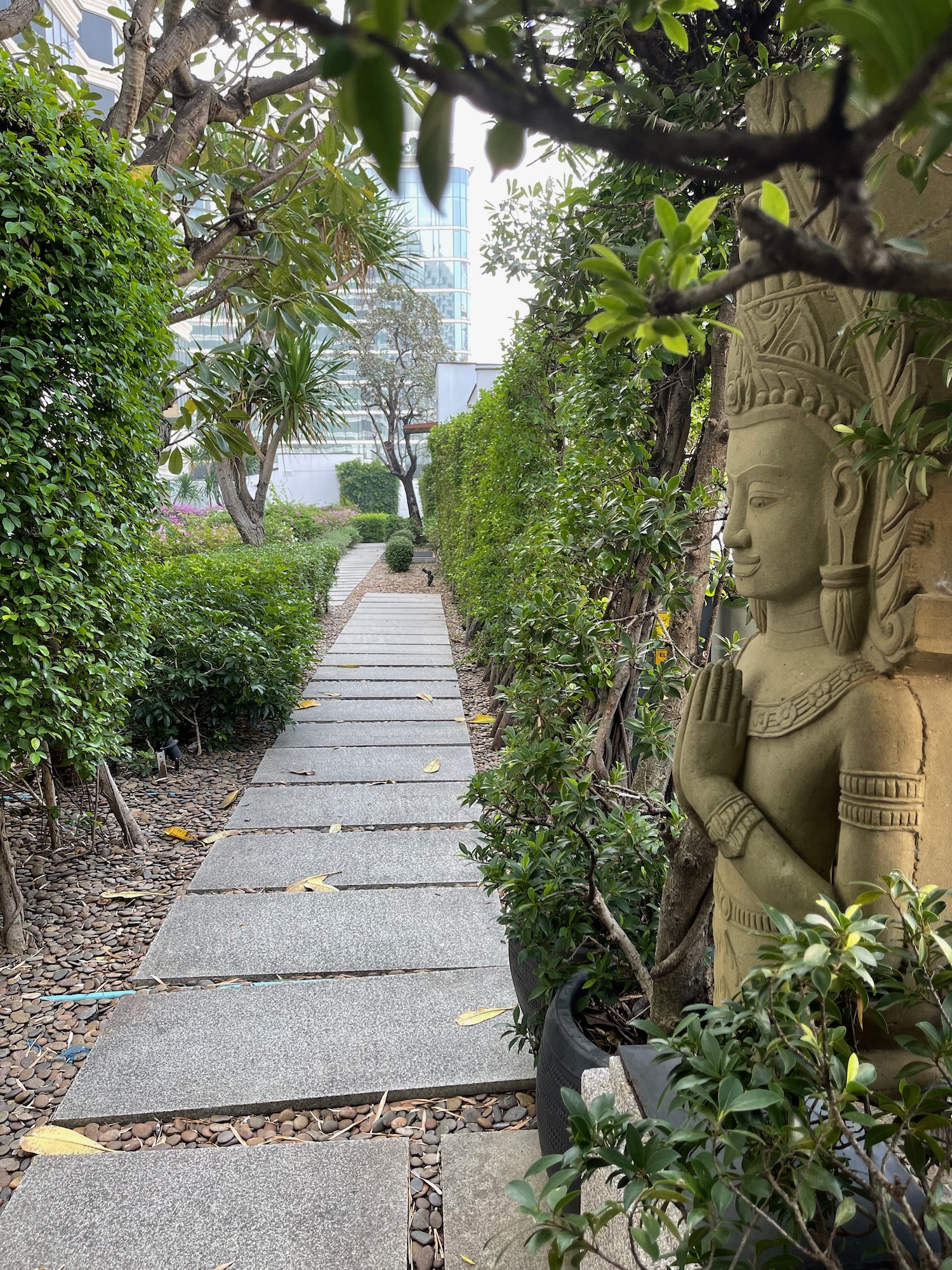 a stone path with a statue in the middle of a garden