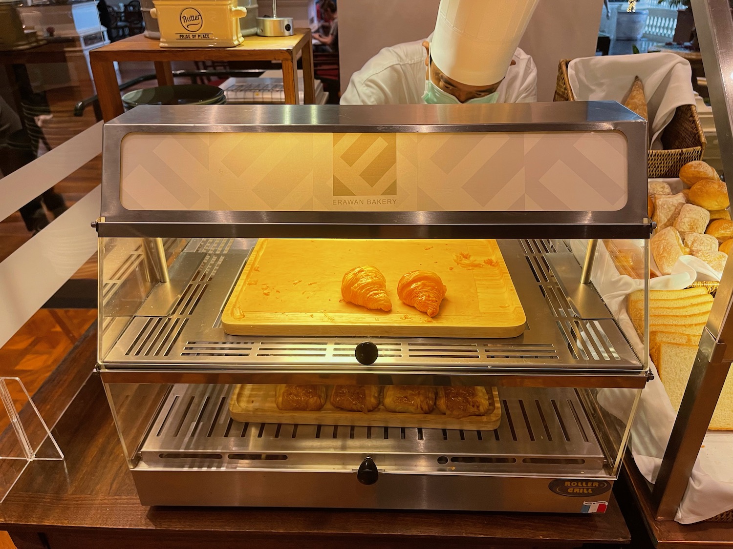 a person in a white hat baking croissants in a oven