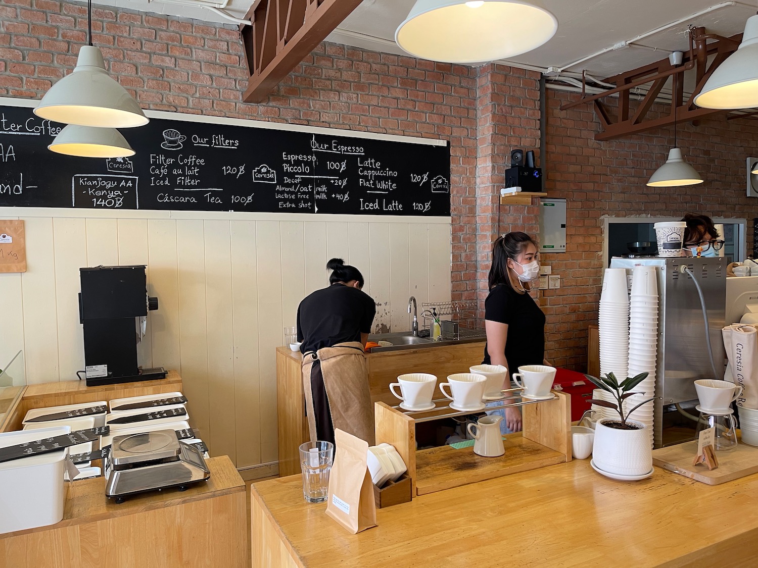 a woman in a mask behind a counter in a coffee shop