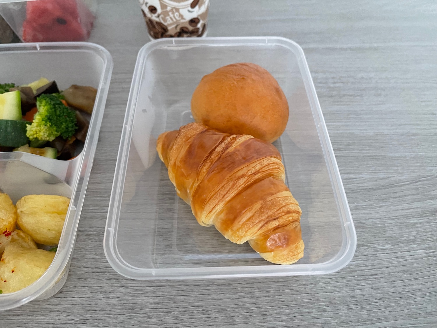 a croissant and a roll in a plastic container