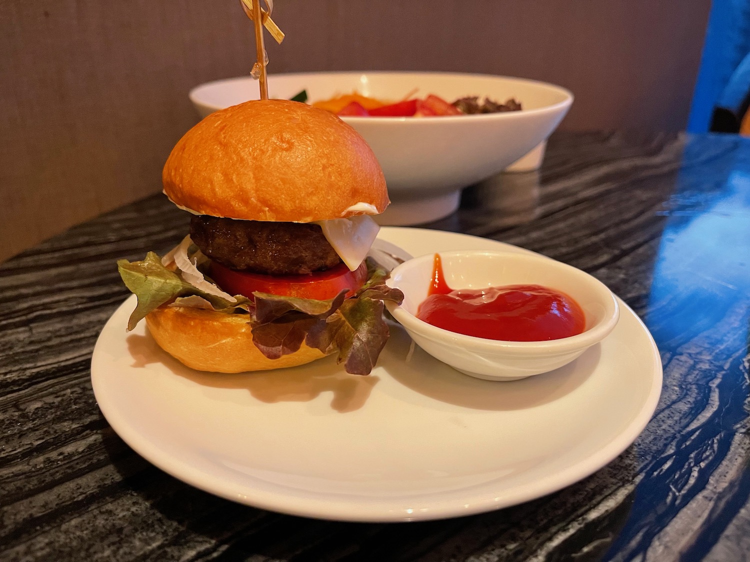 a burger on a plate with a small bowl of ketchup