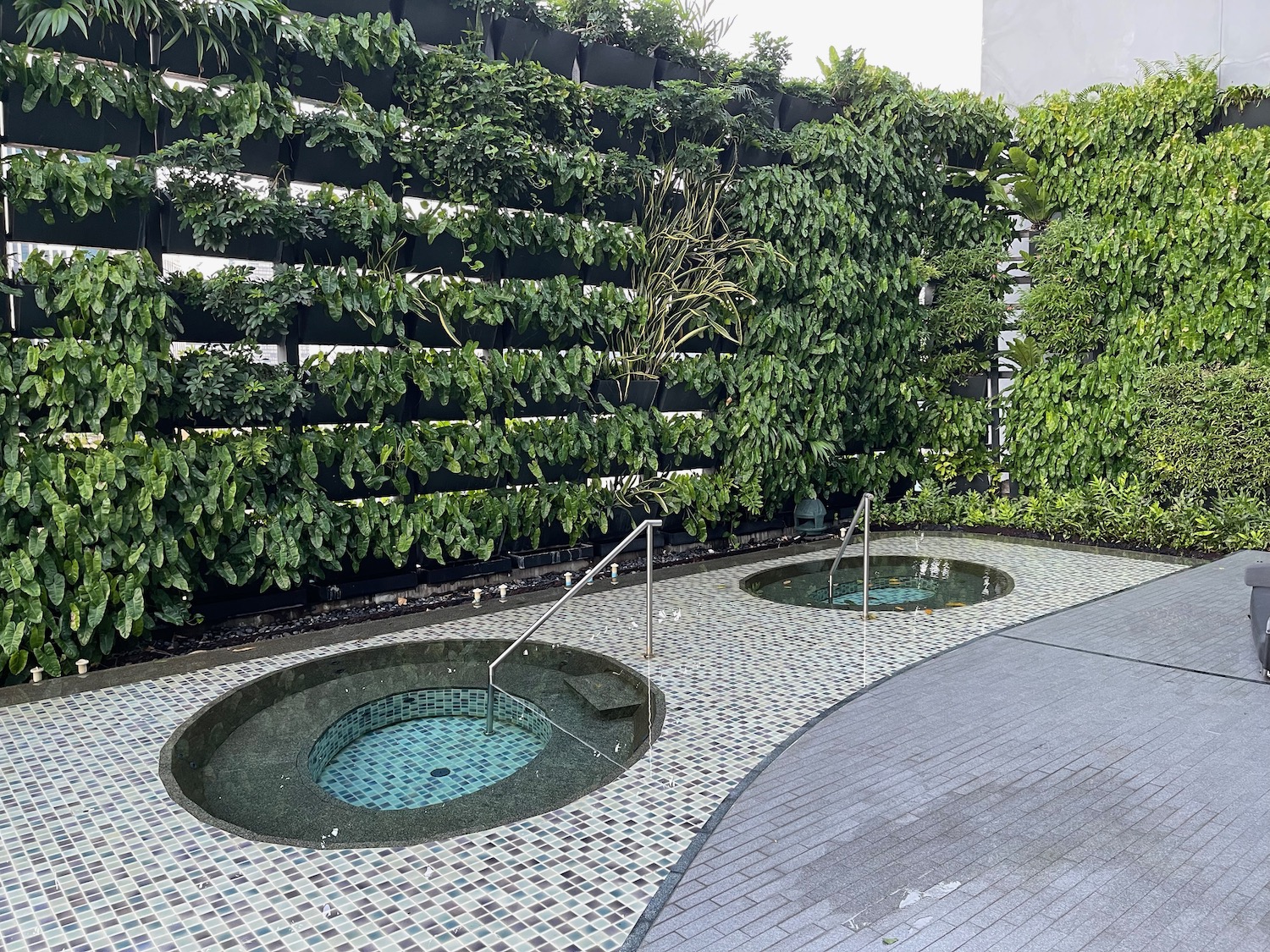 a two round hot tubs with railings in a garden