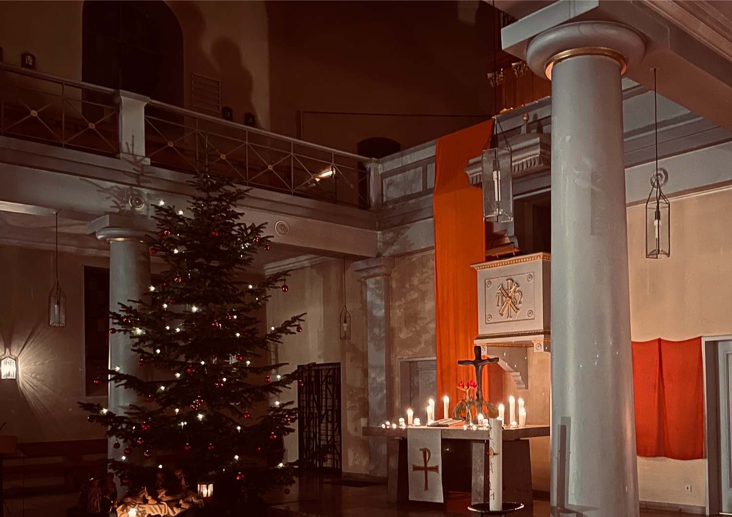 a christmas tree with lights and a cross in a church