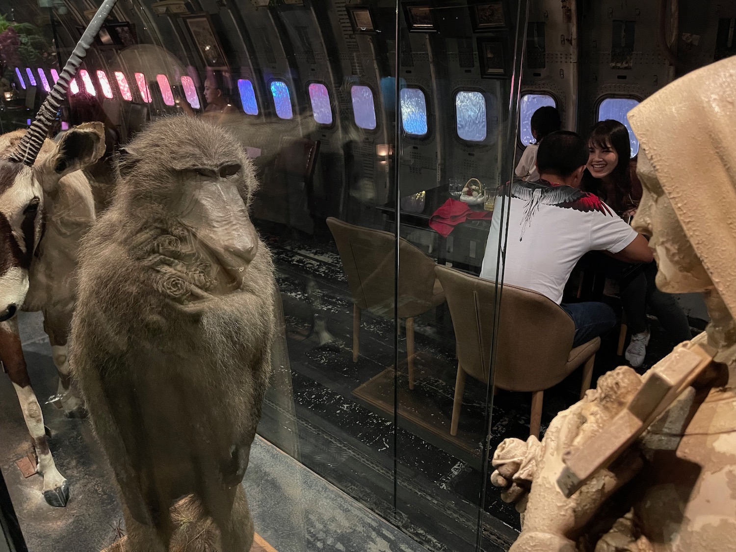 a monkey sitting in a room with people sitting at a table