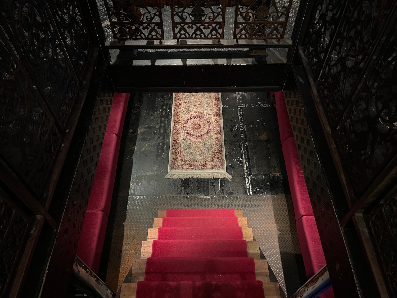 a staircase with red carpet and a rug