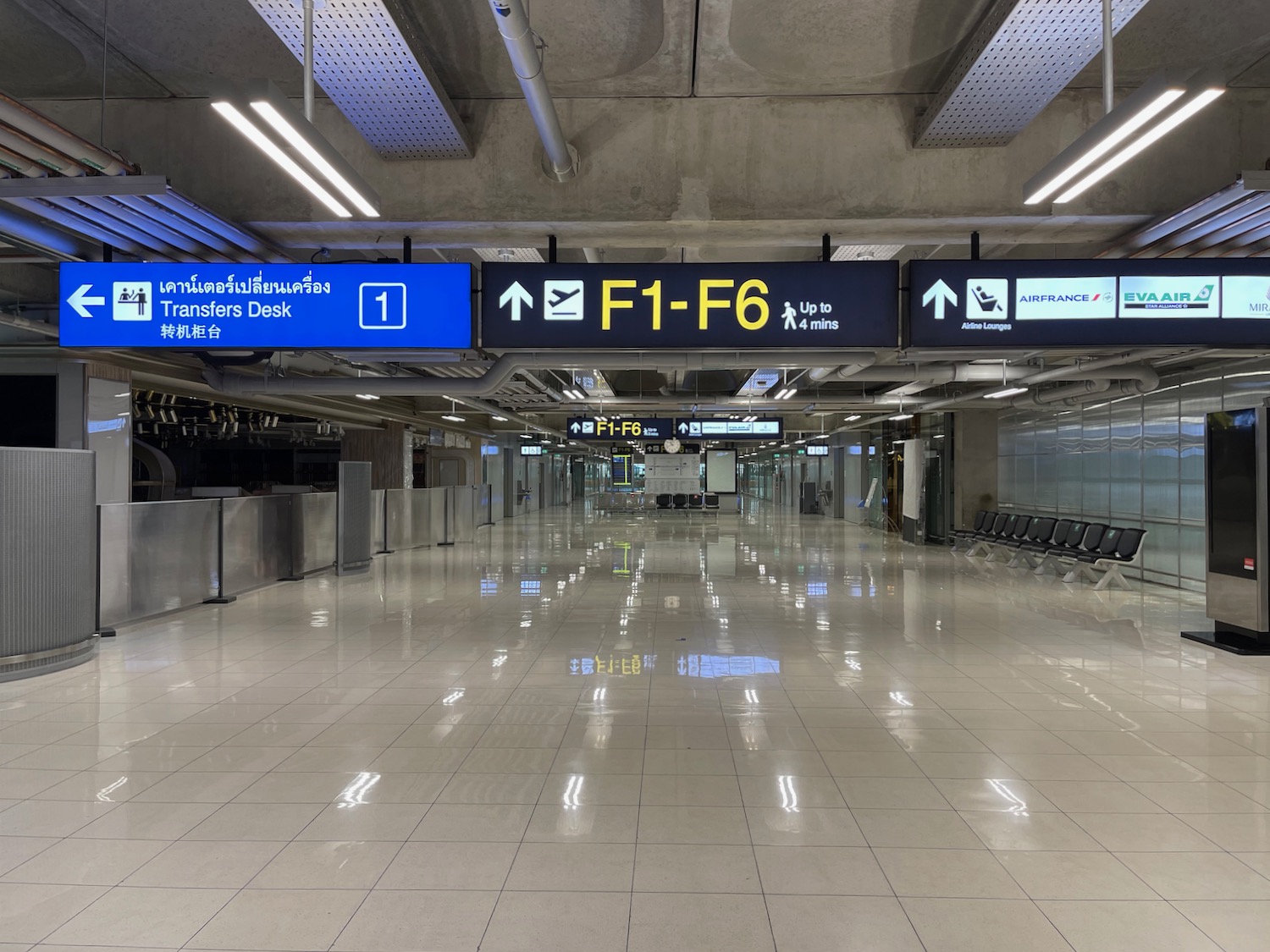 a large airport terminal with signs and chairs