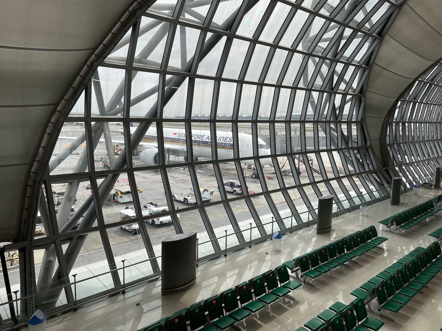 a large glass window with rows of green chairs and airplanes