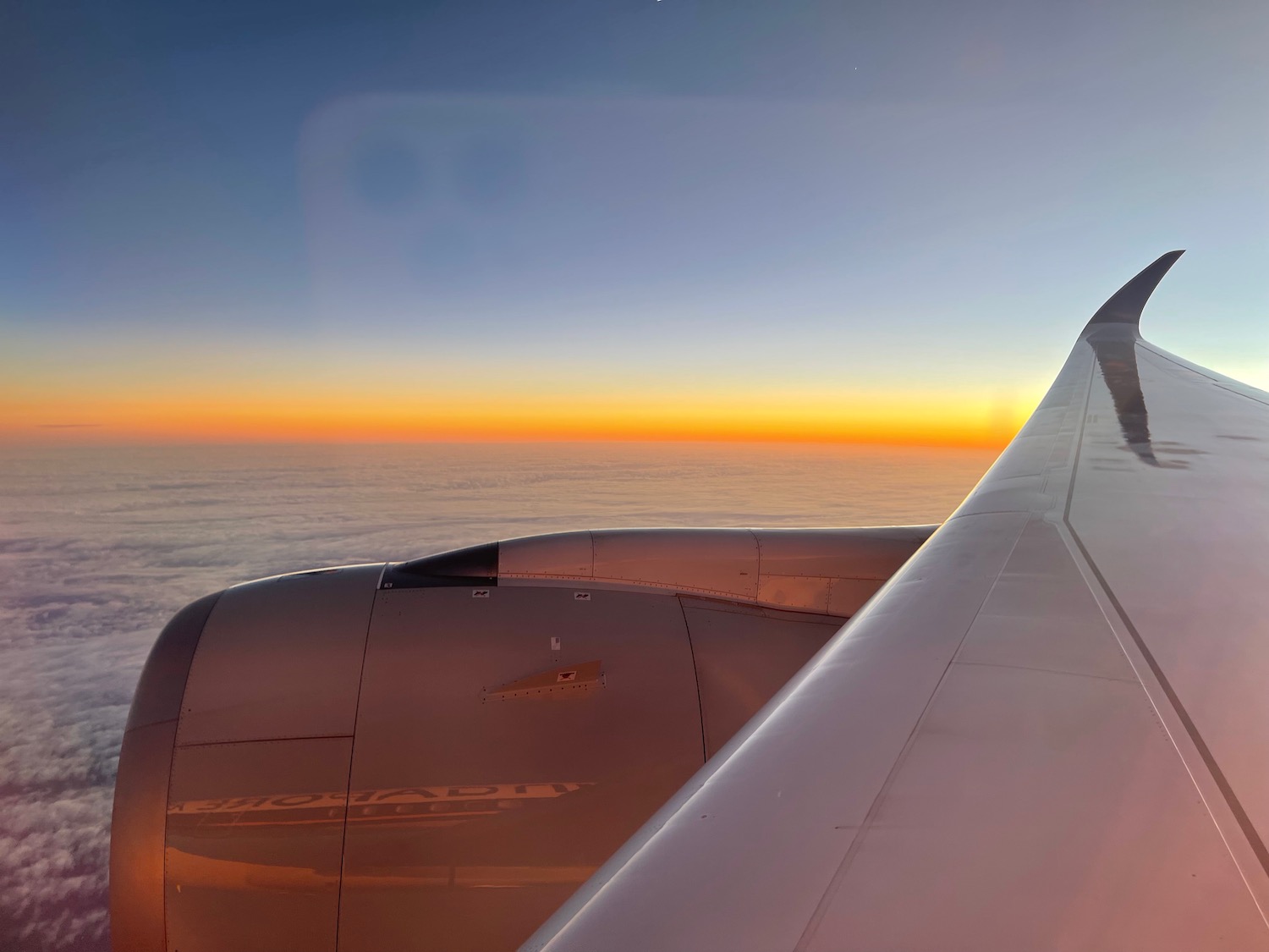 an airplane wing with the sun setting behind it
