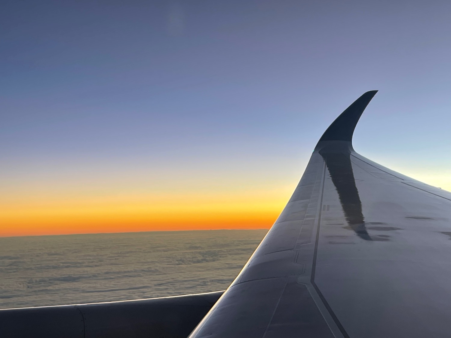 an airplane wing with the sun setting behind it