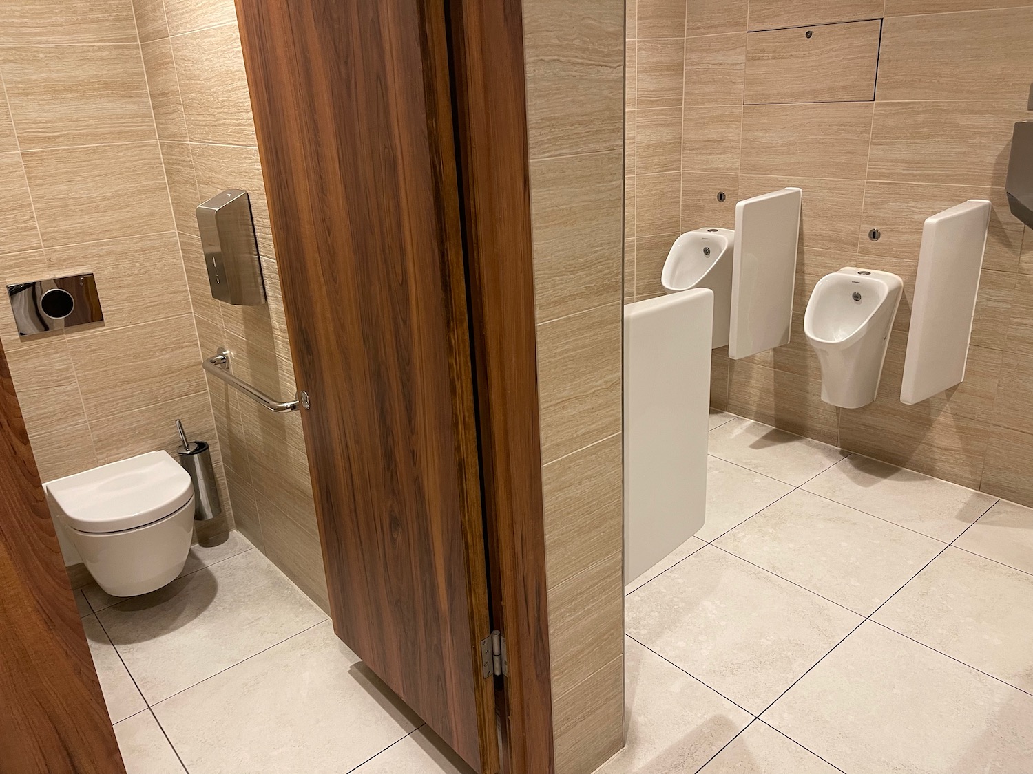 a bathroom with urinals and a wood door