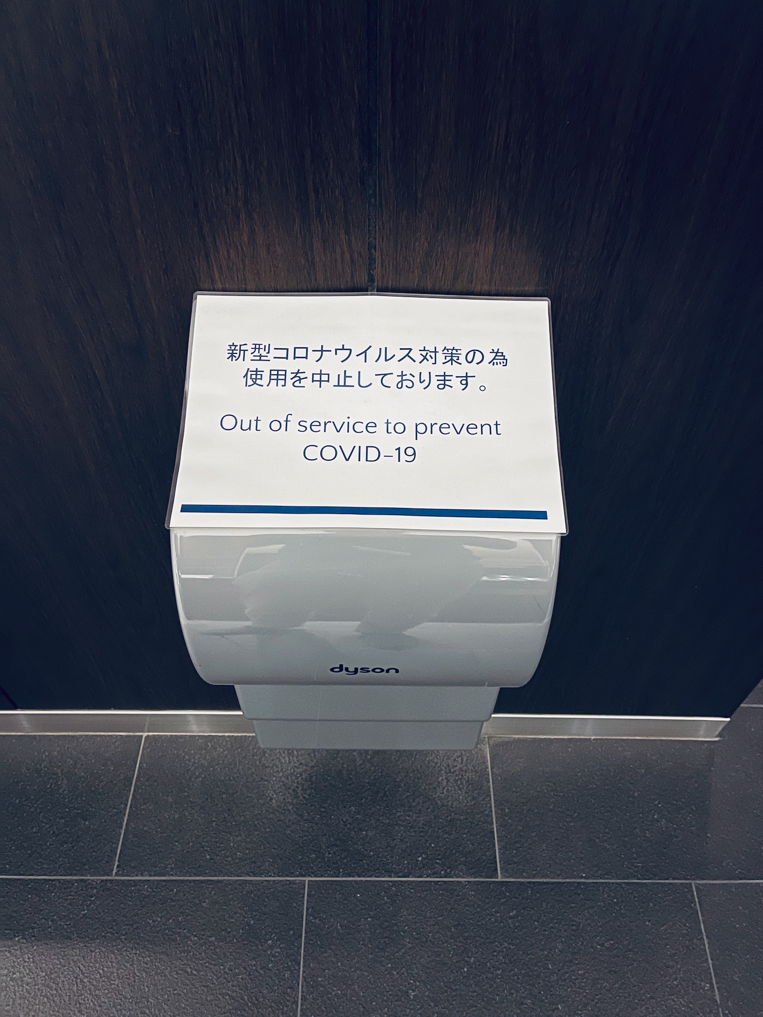 a white paper towel dispenser with a sign on the wall