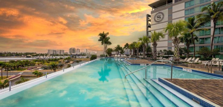 a pool with steps and palm trees in front of a building