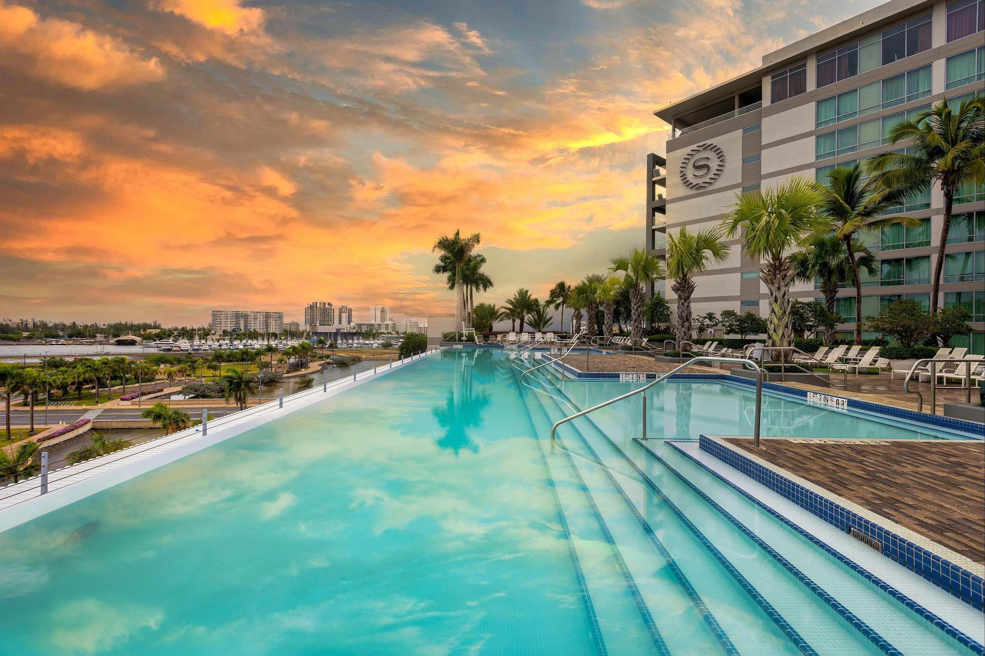 a pool with steps and palm trees in front of a building