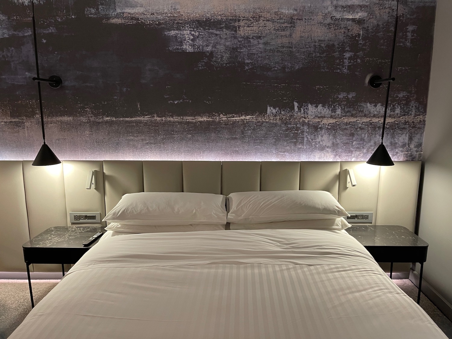 a bed with white sheets and lamps