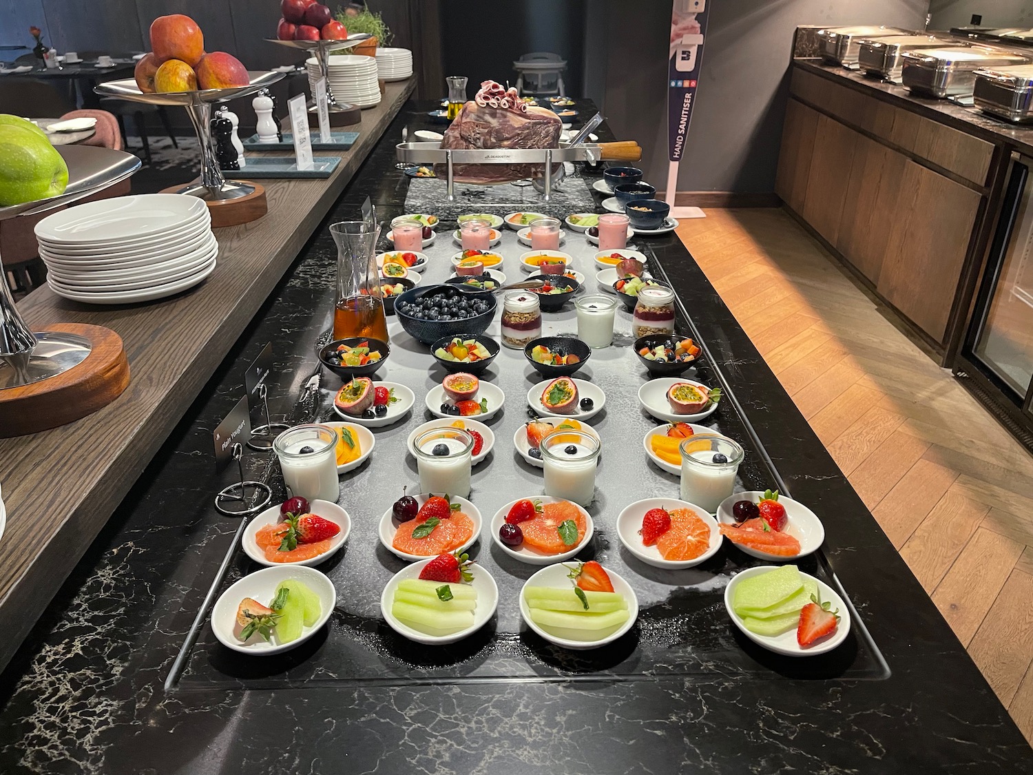 a buffet table with plates of fruit and yogurt