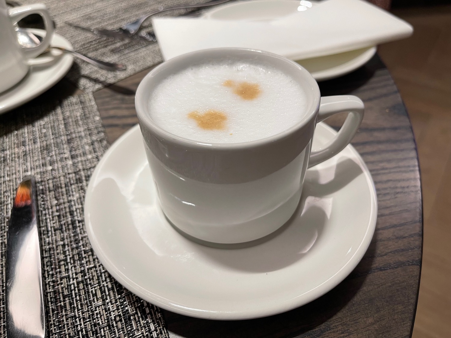 a white cup with foam on a saucer