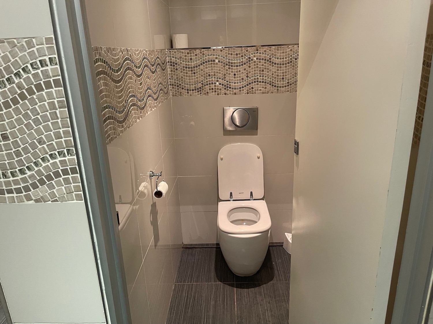 a bathroom with a toilet and a tile wall