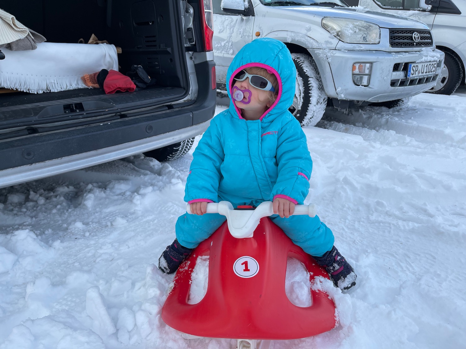 a child sitting on a toy in the snow