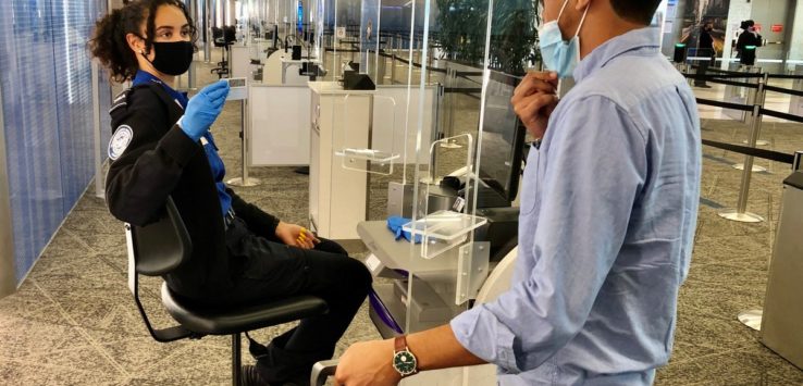 a woman wearing a mask and gloves sitting in a chair in a airport