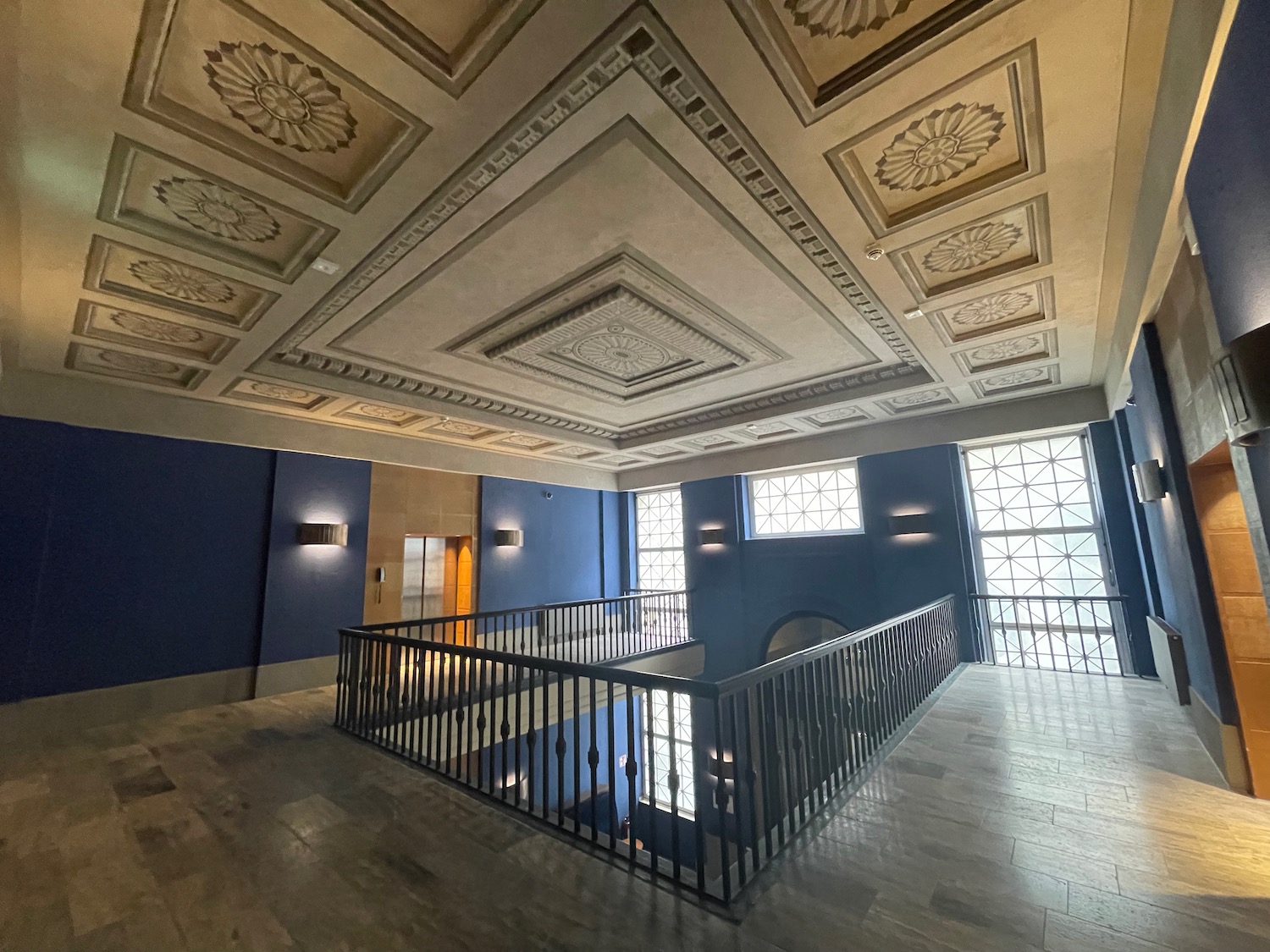 a large room with a railing and a blue wall