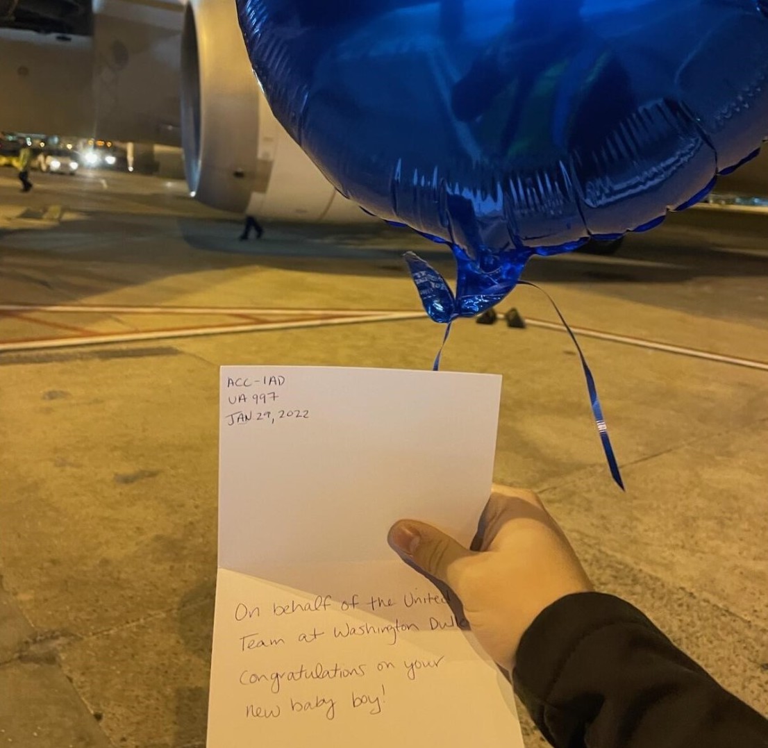 a hand holding a blue balloon and a piece of paper