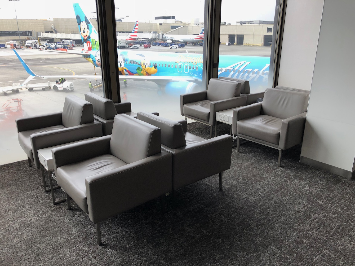 a group of chairs in a room with windows and airplanes in the background