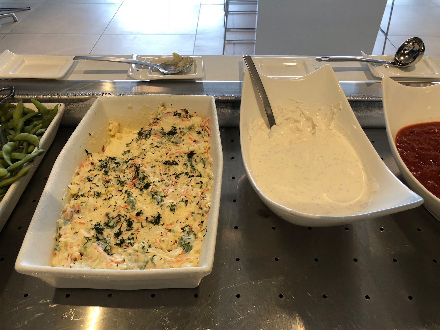 a trays of food in a white bowl and a white bowl with a spoon
