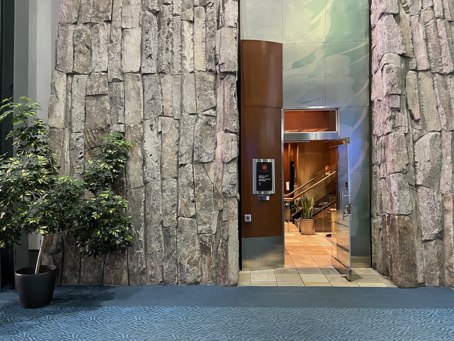 a elevator with a glass door and a stone wall