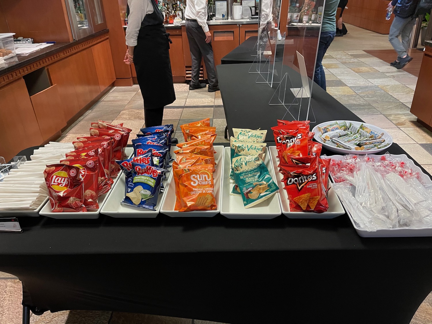a group of people standing next to a table with snacks