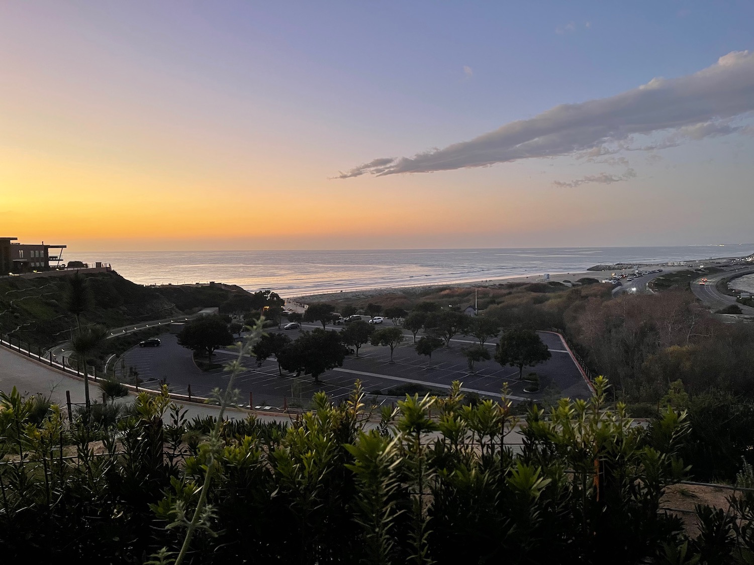 a parking lot with a beach and ocean in the background