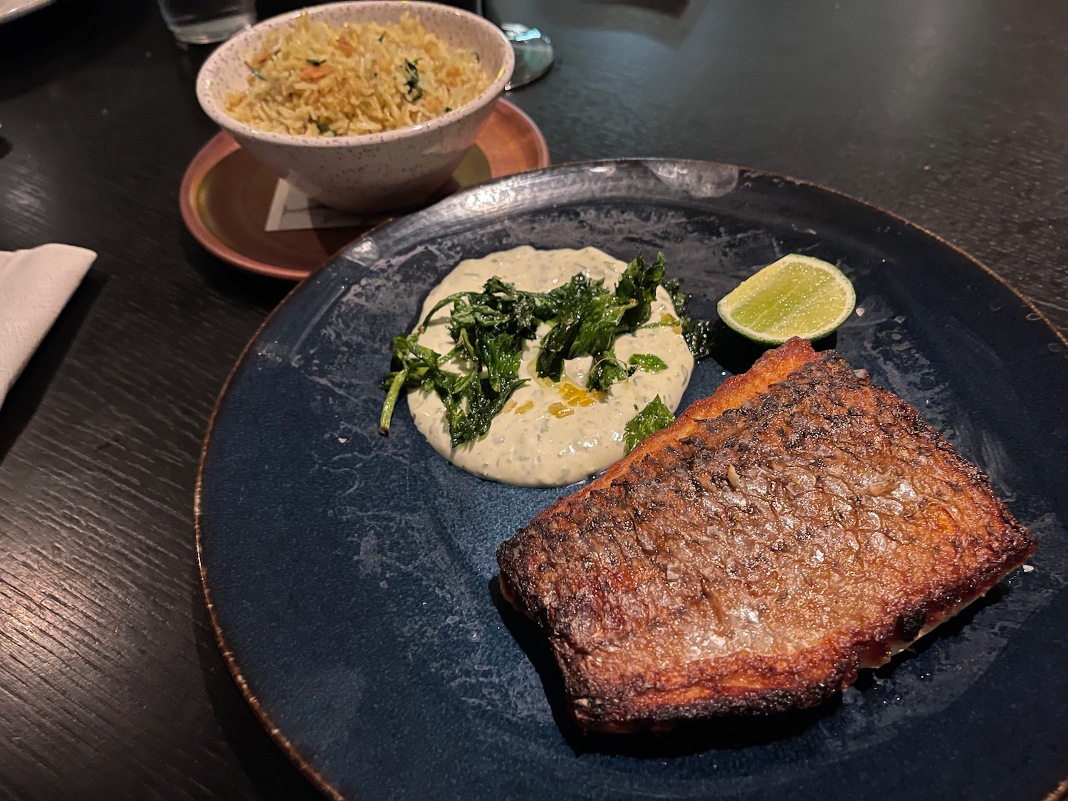 a plate of food with a lime wedge and a bowl of rice