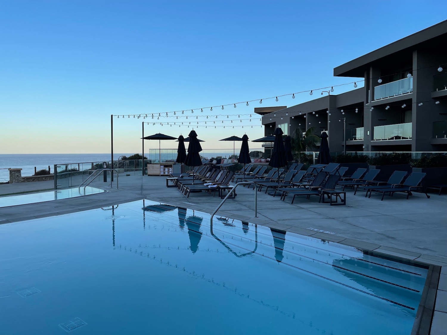 a pool with chairs and umbrellas by a building