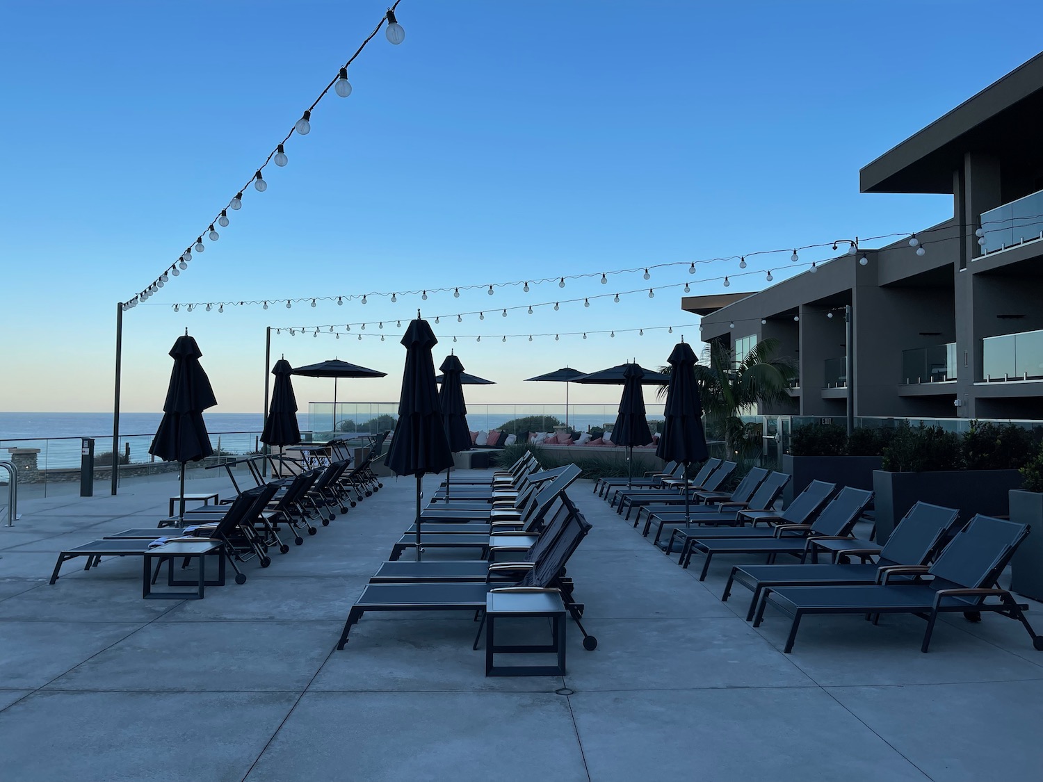 a group of lounge chairs and umbrellas on a patio