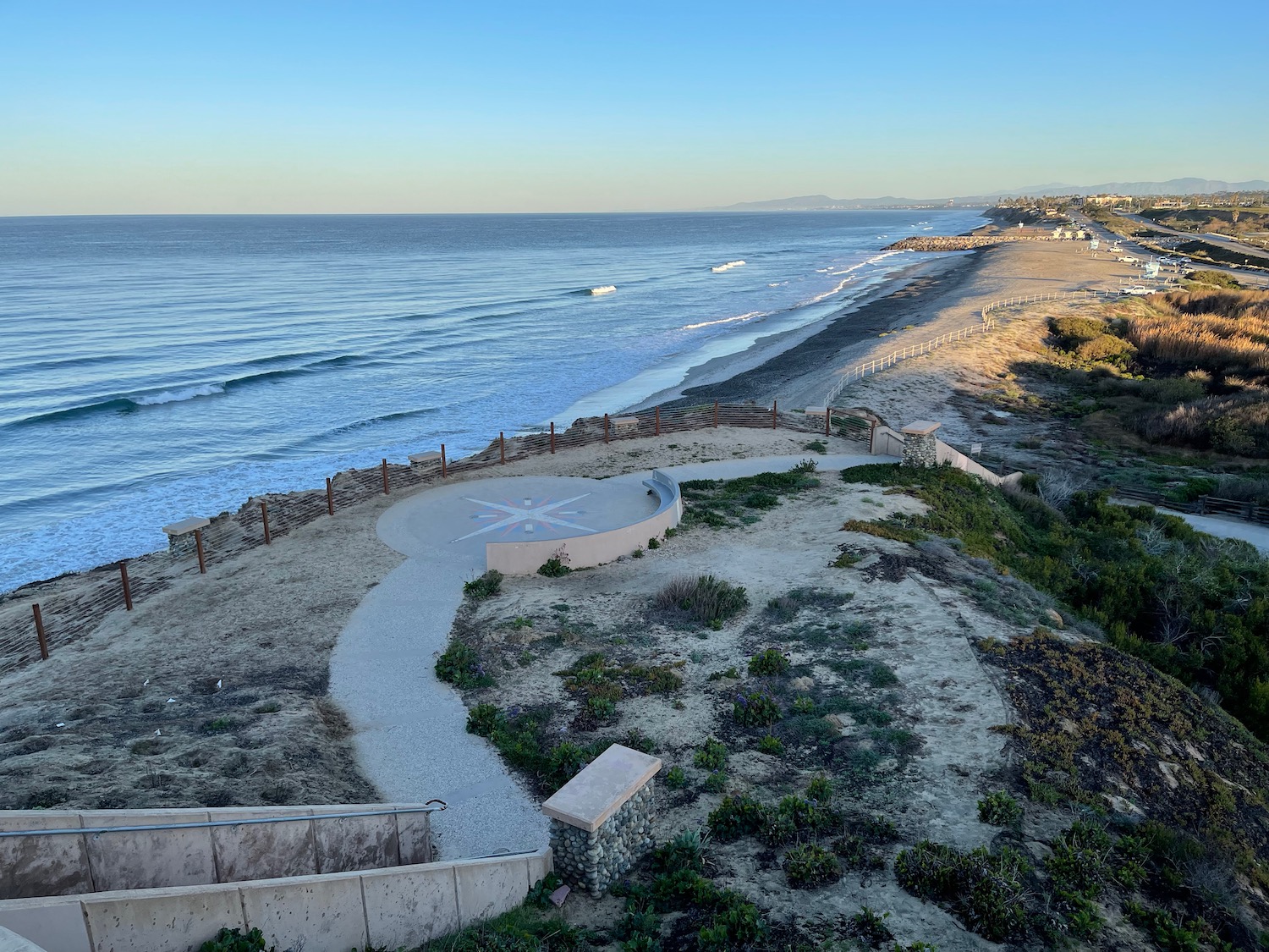 a beach with a walkway and a body of water