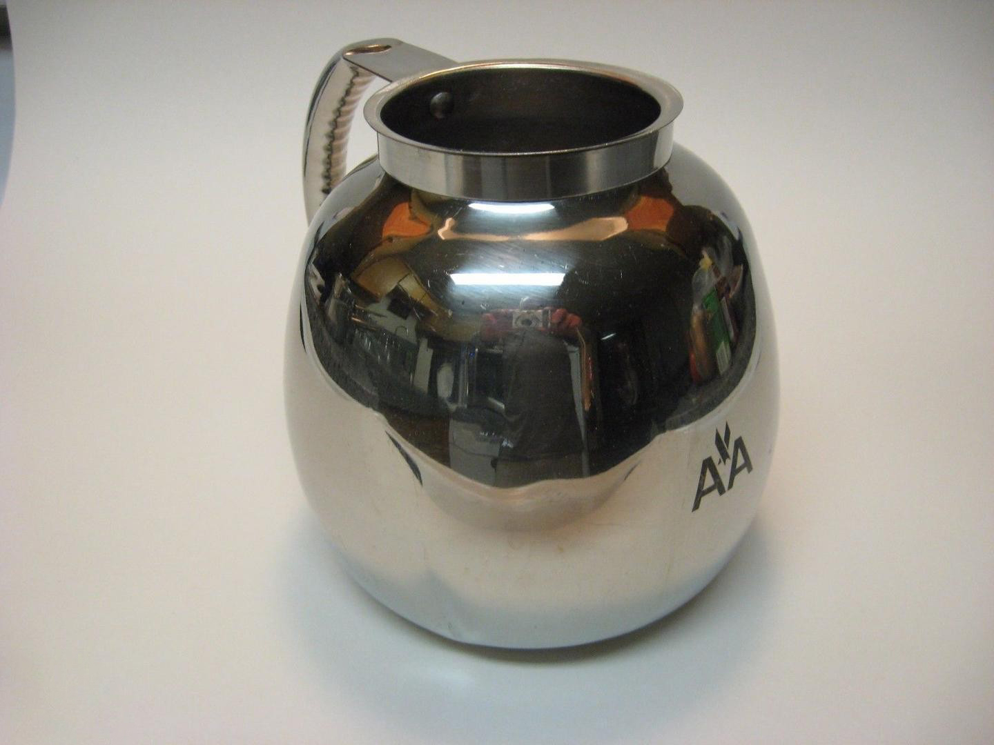 a silver metal pitcher with a handle