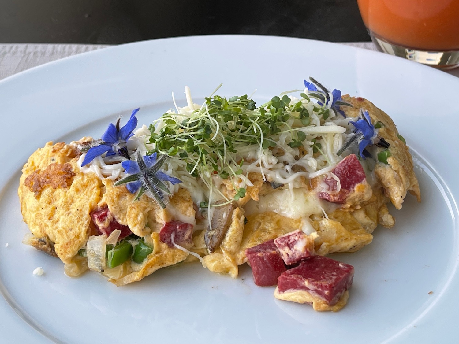 a plate of omelette with flowers and sprouts