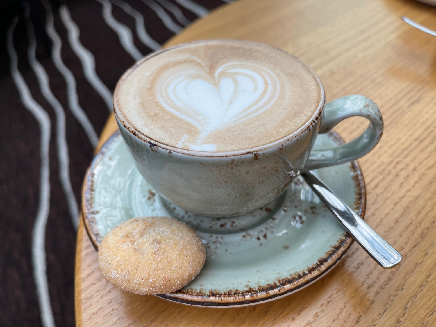 a cup of coffee with a heart design on top of a cookie