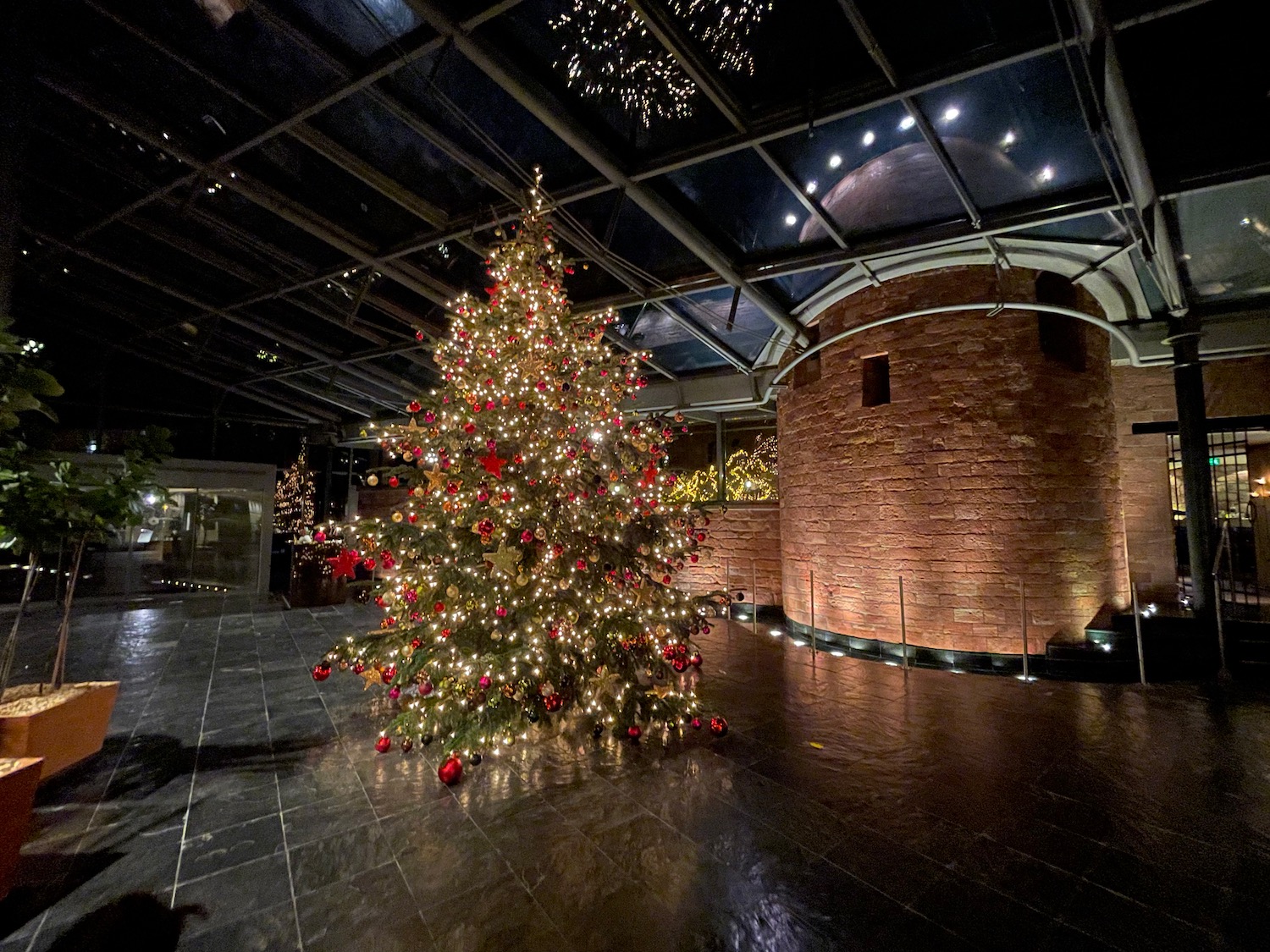 a christmas tree with lights and a brick wall